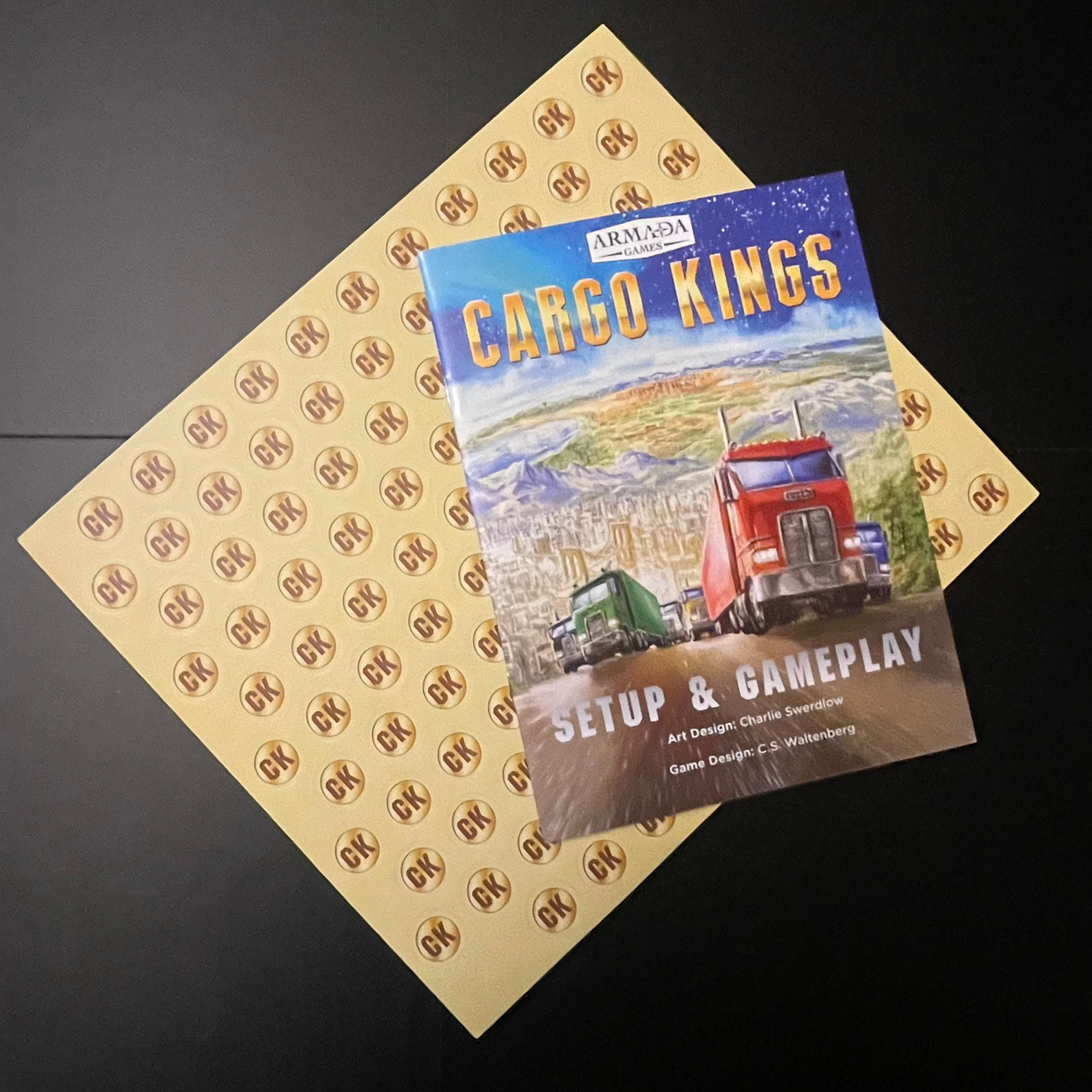 Cargo Kings Setup & Gameplay book on top of cardboard punch-out coins.